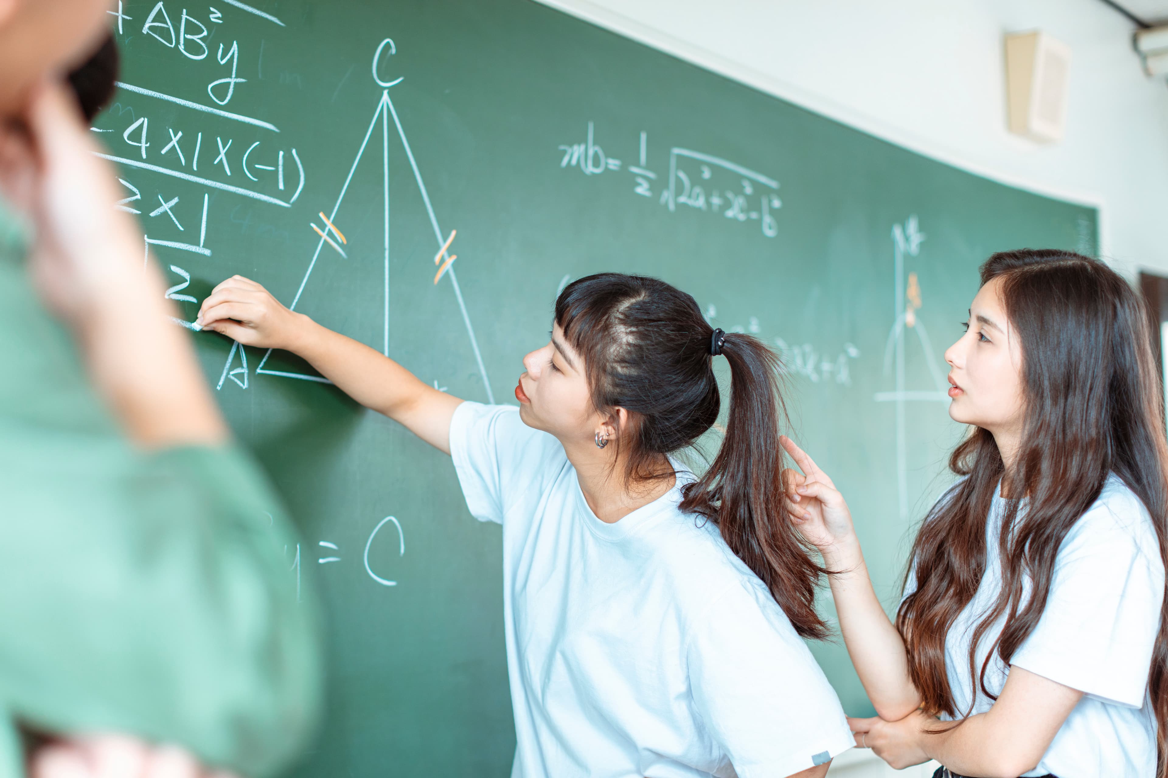 Student solving equations on a chalkboard